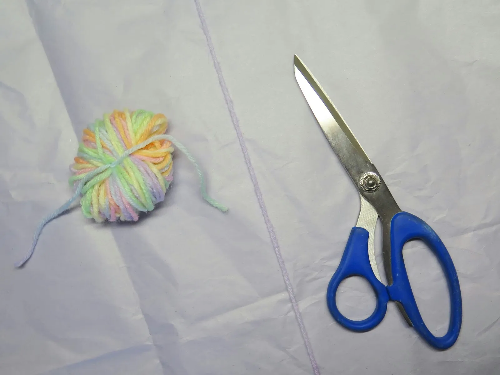 A bundle of yarn next to scissors with a blue handle