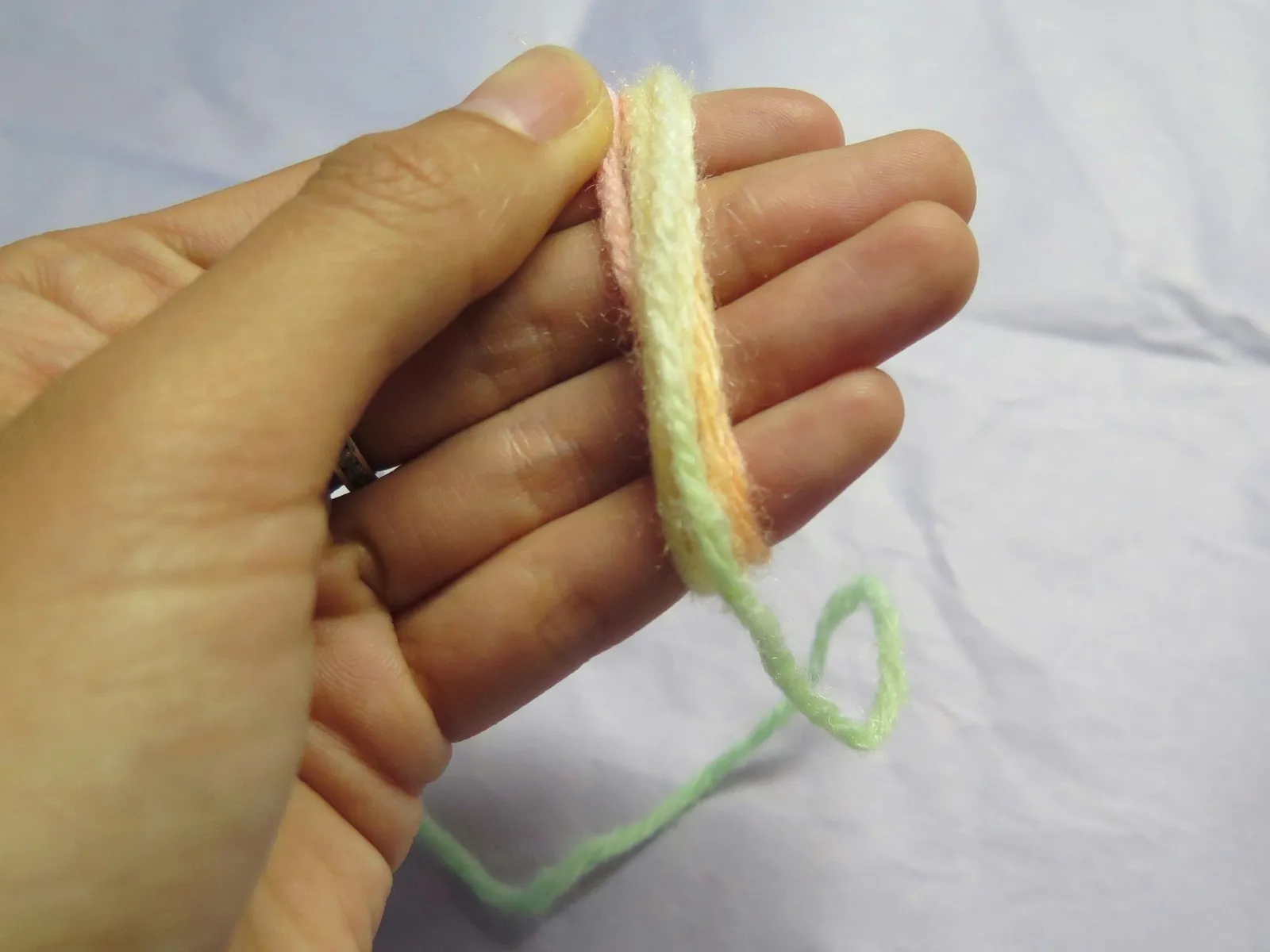 Wrapping a string of yarn around fingers for a DIY pompom bookmark