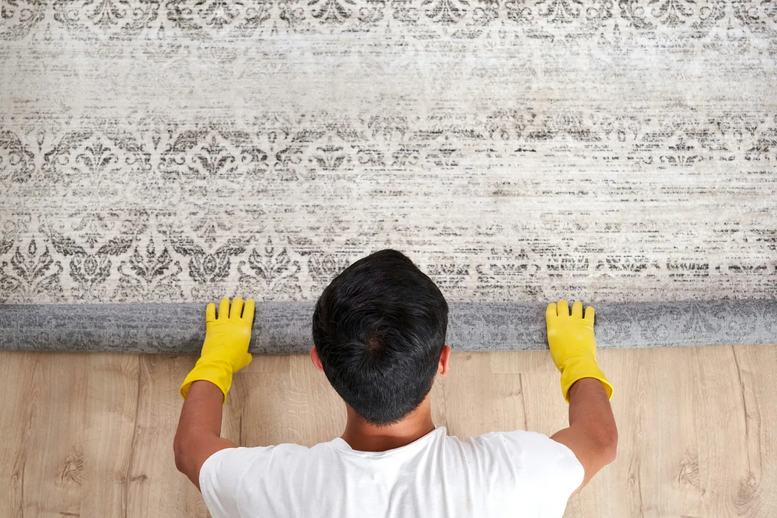 High angle view of man unrolling carpet. Cleaning service concept