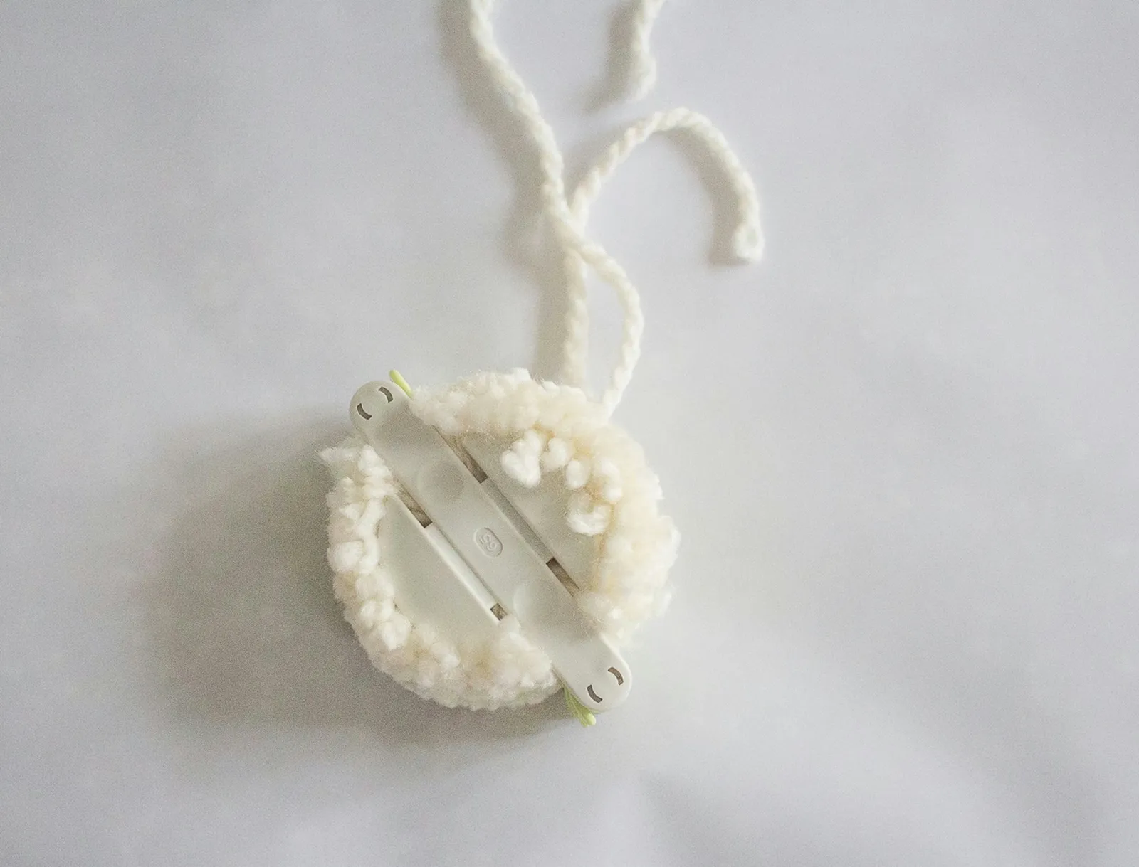 Tie yarn around middle of pom-pom maker
