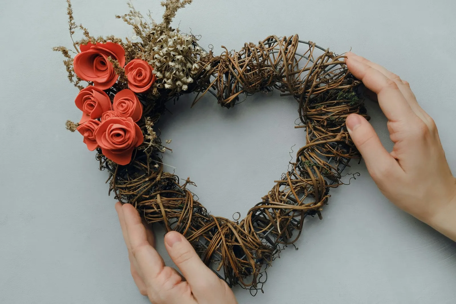 Female hans holding heart shaped floral wreath
