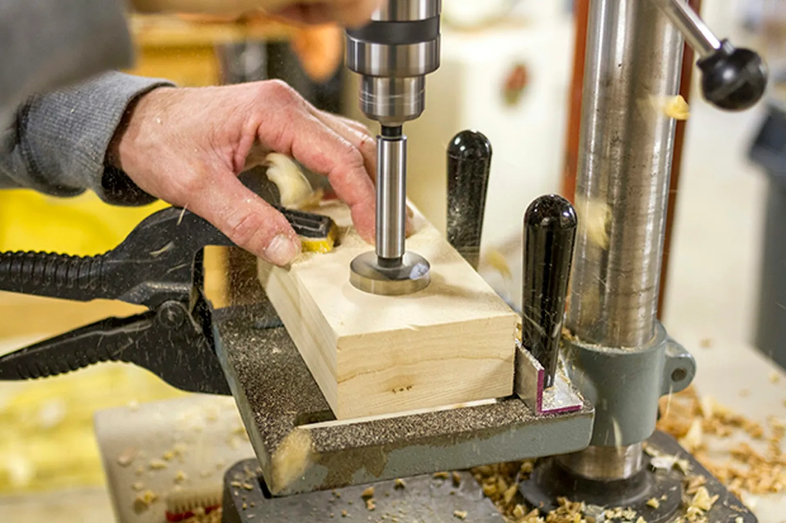 Drill one larger hole into the wood block for the vase to go into.