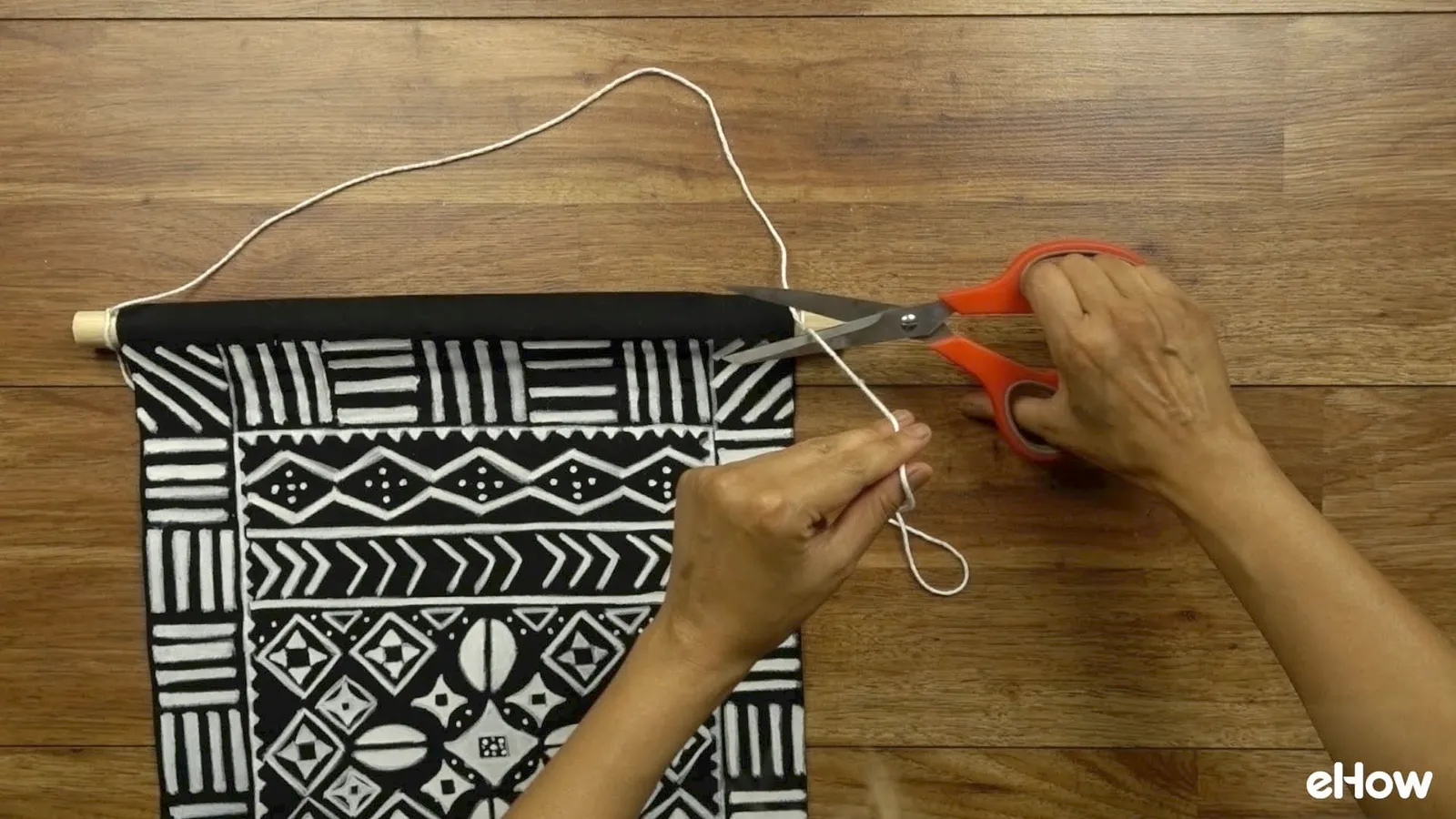Preparing to hang DIY mudcloth-inspired wall hanging.