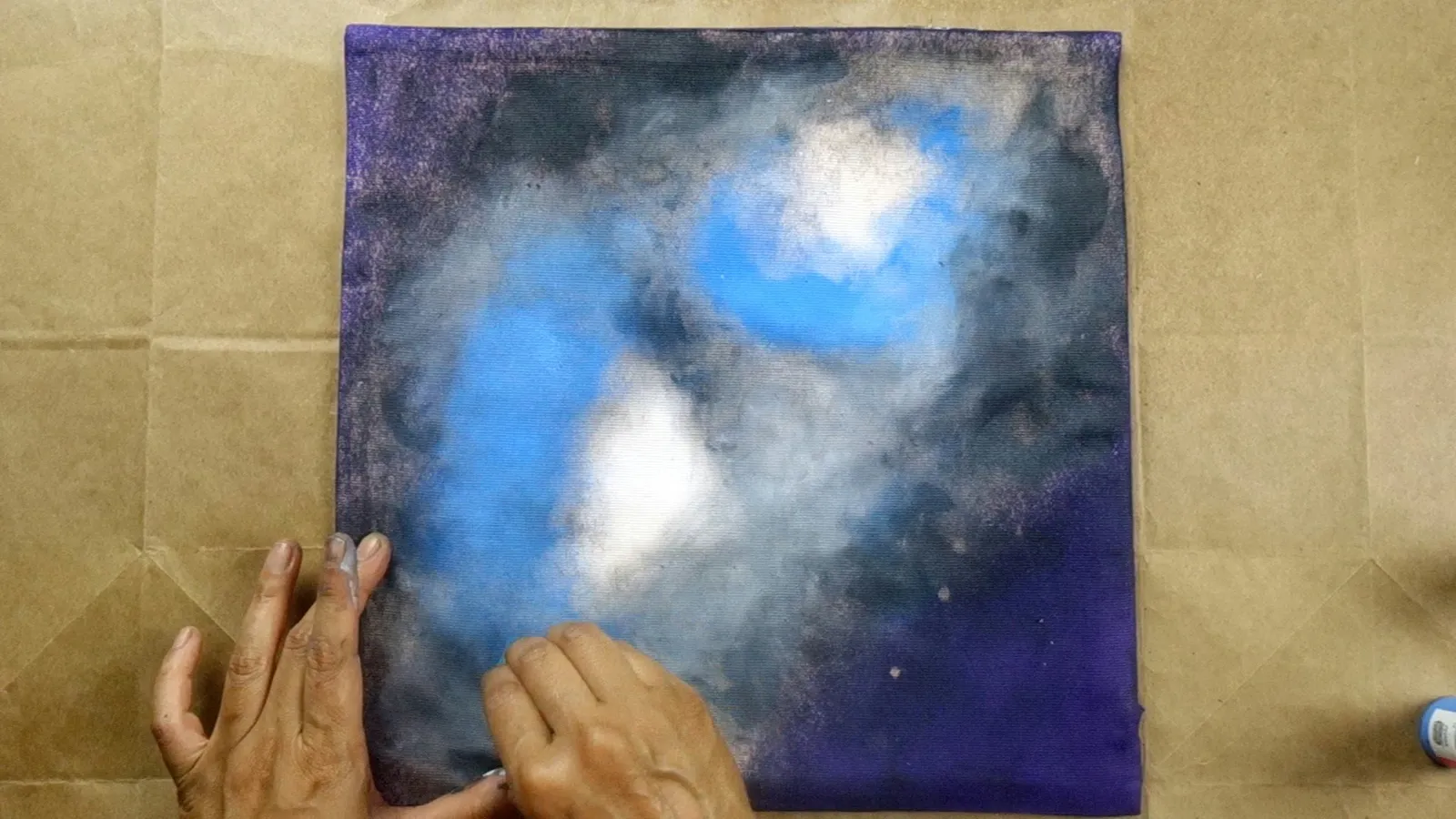Sponging fabric paint onto cushion cover in circular motion.