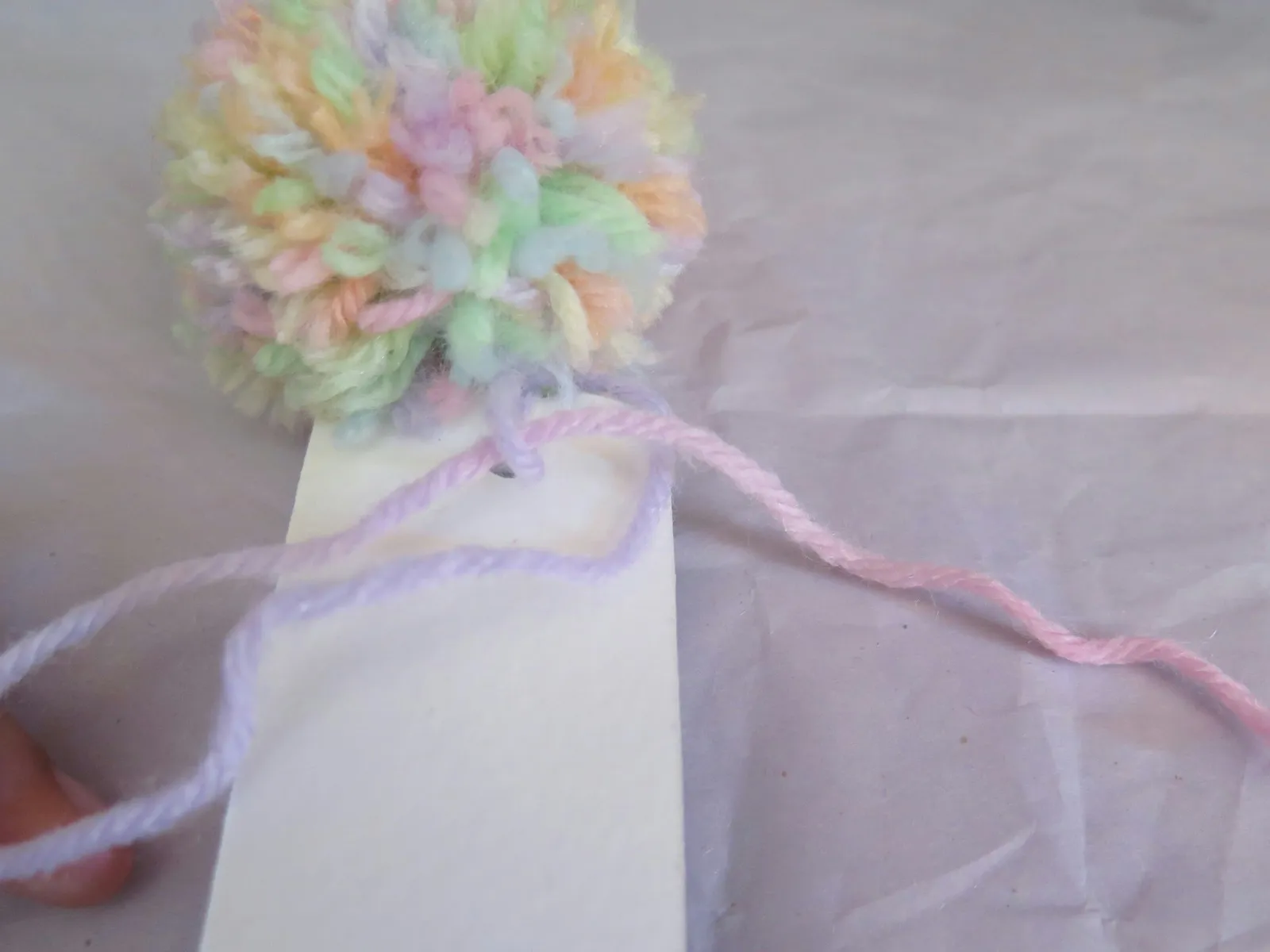 Knotting the tail of yarn for a pompom bookmark