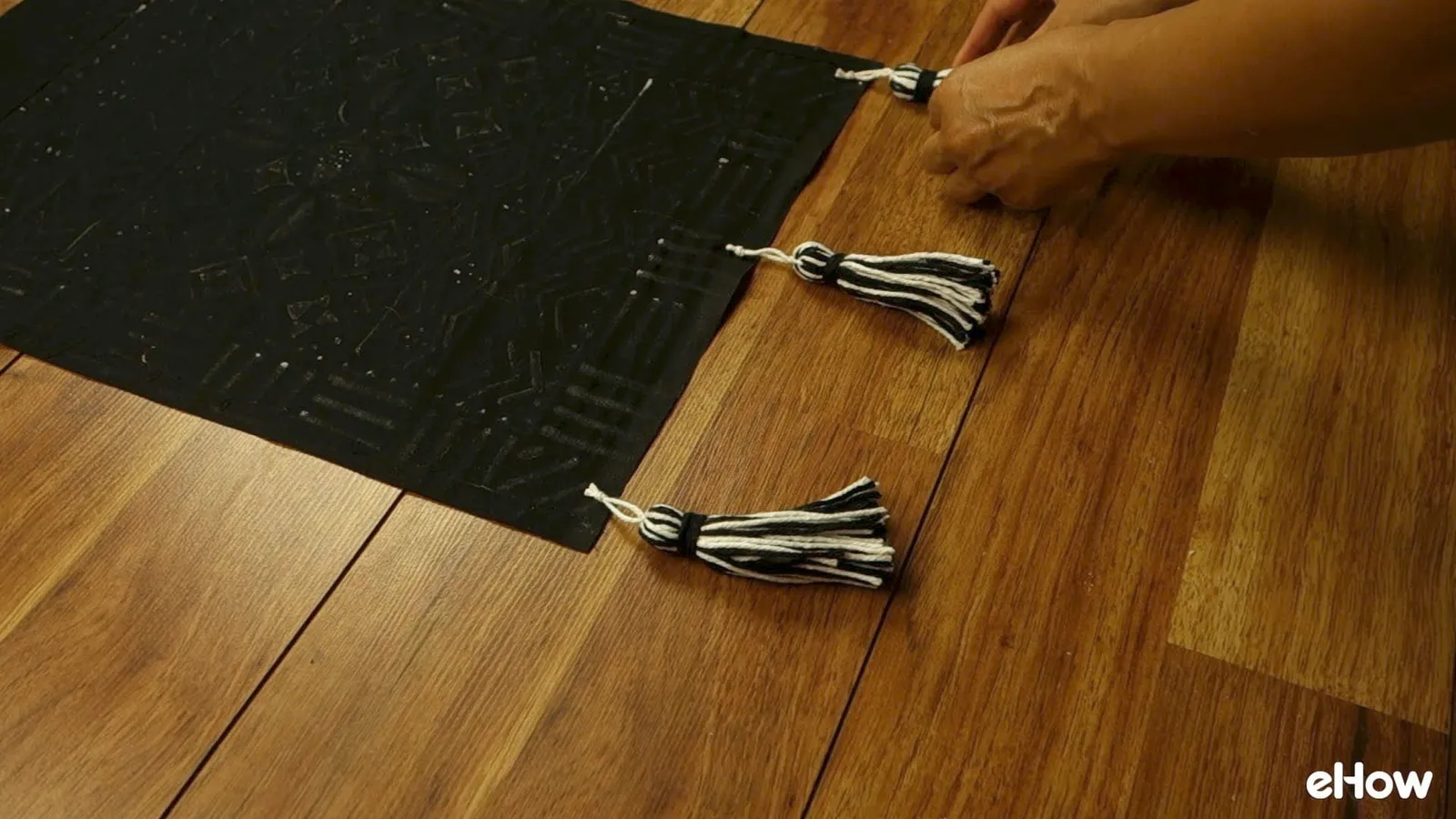 Attaching tassels to DIY mudcloth-inspired wall hanging.